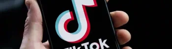 Una mano sujetando su móvil abriendo la aplicación de tiktok